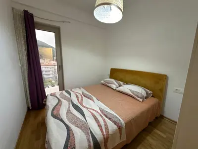 a bedroom with a bed with a window and a light at Jovana Apartments 2 in Budva