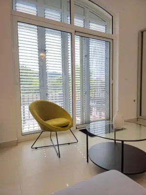 a yellow chair and two tables in a room with large windows at Boulevard Apartments in Kotor