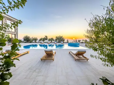 a pool with chairs and a sunset in the background at Villa Carevic with Indoor & Outdoor Pool in Kotor