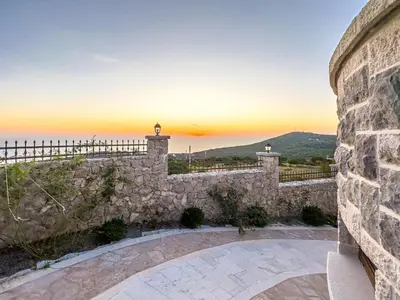 a stone wall with a sunset in the background at Villa Carevic with Indoor & Outdoor Pool in Kotor