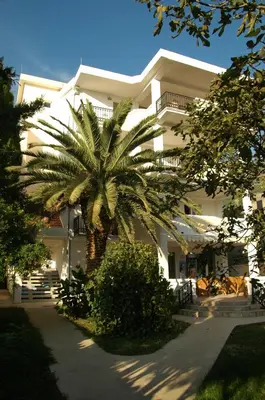 a palm tree in front of a white building at Solaris Summer Resort Apartments in Sutomore