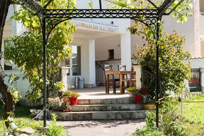 a garden with an arbor with stairs and a table at Solaris Summer Resort Apartments in Sutomore