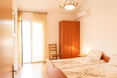 a bedroom with a bed and a chair in it at Solaris Summer Resort Apartments in Sutomore