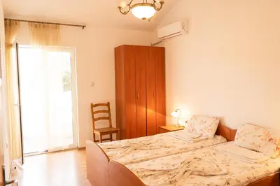 a bedroom with a bed and a chair and a window at Solaris Summer Resort Apartments in Sutomore