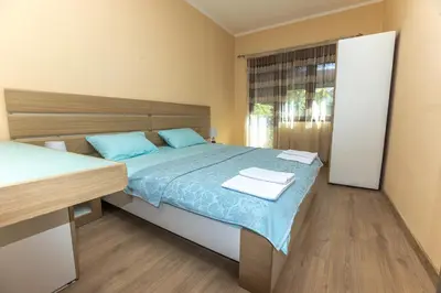 a bedroom with a bed with blue sheets and a window at Apartmani Bulevar in Cetinje