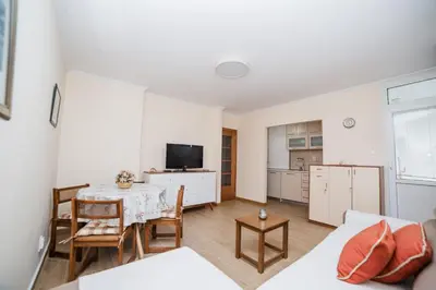 a living room with a table and a kitchen at Pizana Budva Central in Budva