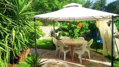 a table and chairs under a white umbrella at Luiggi in Kotor