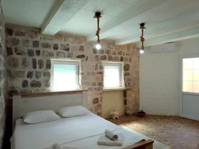 a bedroom with a white bed and two windows at Luiggi in Kotor