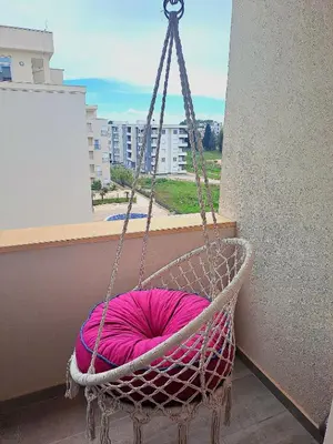 a hanging chair with a pink pillow in a balcony at Apartment AS in Ulcinj