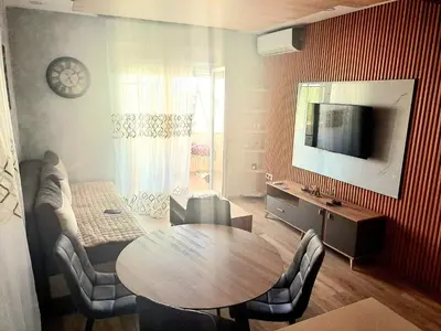a living room with a table and chairs and a television at Apartment AS in Ulcinj