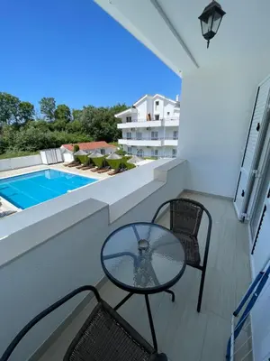 a balcony with a glass table and chairs and a swimming pool at Residence LEORA in Ulcinj