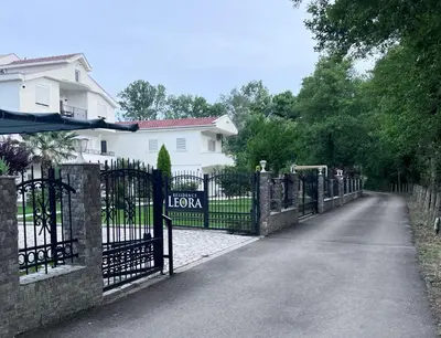 a fence in front of a house with a driveway at Residence LEORA in Ulcinj