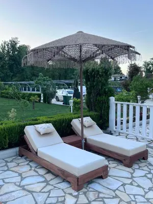 two beds under an umbrella on a patio at Residence LEORA in Ulcinj