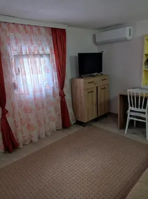 a room with a curtain and a tv and a chair at Olga 112 in Bar