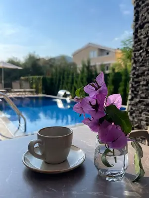 a vase with purple flowers and a cup on a table at Viola Hotel Budva in Budva