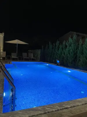 a blue swimming pool at night with an umbrella at Viola Hotel Budva in Budva