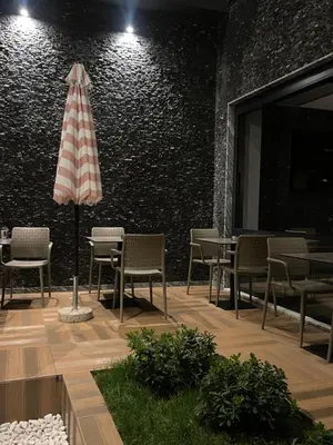 a patio with chairs and an umbrella in front of a wall at Viola Hotel Budva in Budva
