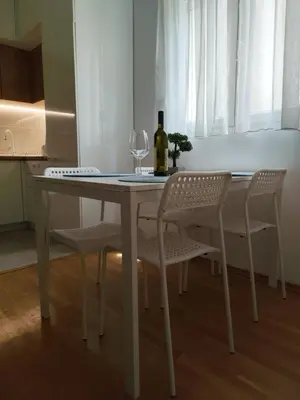 a white table with two chairs and a bottle of wine at Kan in Podgorica