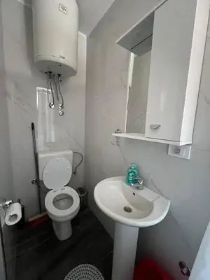 a white bathroom with a toilet and a sink at Kontiki Apartments 2 in Ulcinj