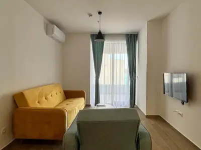 a living room with a yellow couch and a window at Rafailovici Beachfront Apartment 2 in Budva