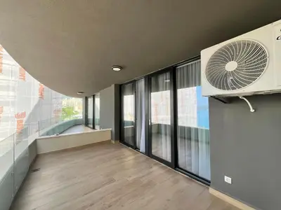 an empty room with a fan and large windows at Rafailovici Beachfront Apartment 2 in Budva