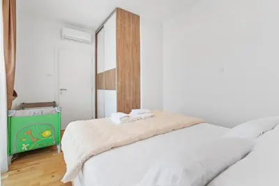 a white bedroom with two beds and a mirror at ID LUX APARTMENTS in Becici