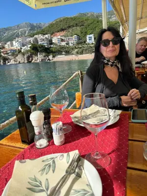 a woman sitting at a table with wine glasses at Private Patio Przno Steps to Beach 2 Bedroom 2 Parkings BBQ Villa Olive in Sveti Stefan