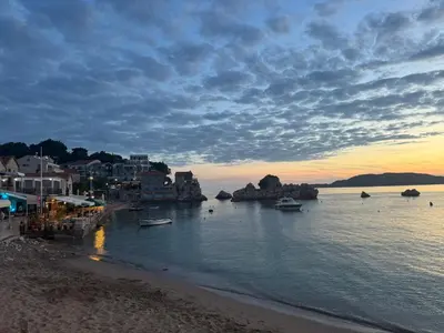 a beach with boats in the water at sunset at Private Patio Przno Steps to Beach 2 Bedroom 2 Parkings BBQ Villa Olive in Sveti Stefan