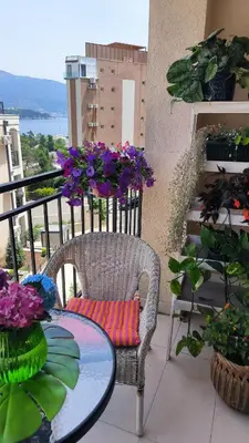 a chair and a table on a balcony with flowers at Centre Budva Blue in Budva