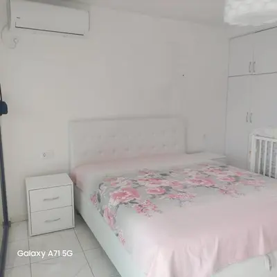 a white bedroom with a bed with a floral bedspread at ALOHA Beach front Vacation Rental in Ulcinj