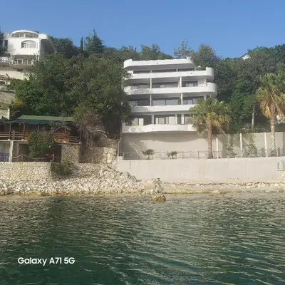 a white building next to a body of water at ALOHA Beach front Vacation Rental in Ulcinj