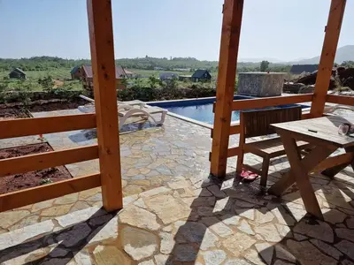 a table and a bench on a patio with a pool at Bungalovi Spahic in Ulcinj