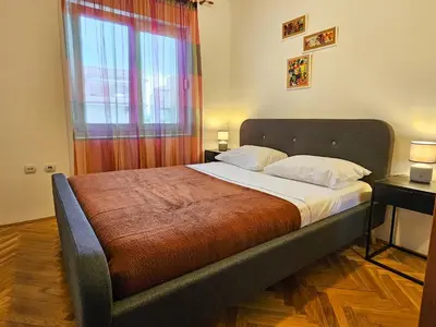 a bedroom with a large bed with a window at Luka's Blok 9 Apartment in Podgorica