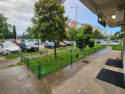 a tree in a fence next to a parking lot at Luka's Blok 9 Apartment in Podgorica