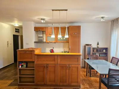 a kitchen with wooden cabinets and a dining table at Luka's Blok 9 Apartment in Podgorica