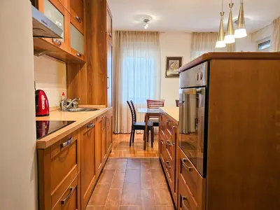 a kitchen with wooden cabinets and a dining table at Luka's Blok 9 Apartment in Podgorica