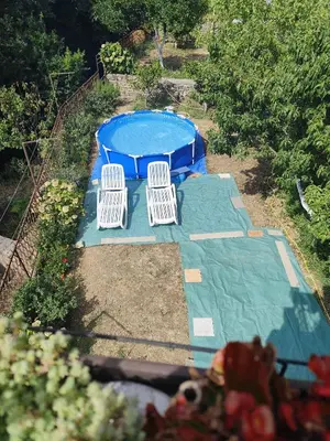 an overhead view of a pool with three white chairs at Apartmani Vučević in Sutomore