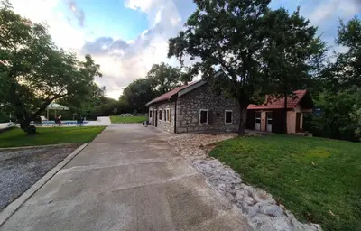 a stone building with a tree next to a street at Holiday home Zlatna Glavica in Podgorica