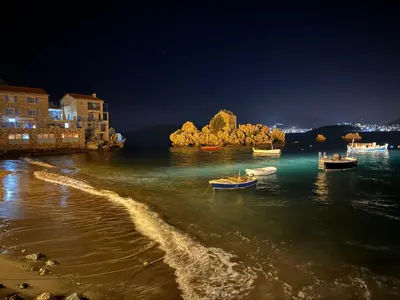 a group of boats in the water at night at Steps to beach 3 Bedrooms 2 Bathrooms 2 Kitchens with a Terrace - 2 Parking spots - Sea View in Sveti Stefan
