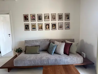 a couch in a living room with pictures on the wall at Steps to beach 3 Bedrooms 2 Bathrooms 2 Kitchens with a Terrace - 2 Parking spots - Sea View in Sveti Stefan