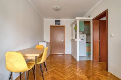 a dining room with a wooden table and yellow chairs at M Apartment Budva in Budva