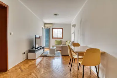 a living room with a table and chairs and a couch at M Apartment Budva in Budva