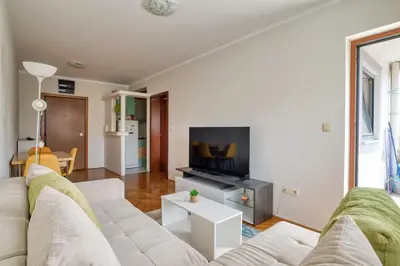 a living room with a white couch and a tv at M Apartment Budva in Budva