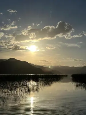 a sunset over a body of water with mountains at Lakeside Harmony Apartment in Golubovci