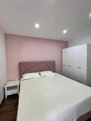a bedroom with a white bed and a pink wall at Agatom in Budva