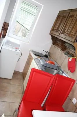 a kitchen with a red chair and a sink at Smještaj Milena Čanj in Čanj