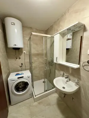 a bathroom with a washing machine and a sink at Cozy 1 bedroom APT with free parking in Podgorica