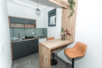 a kitchen with a wooden table and a chair at Bumax Apartments in Ulcinj