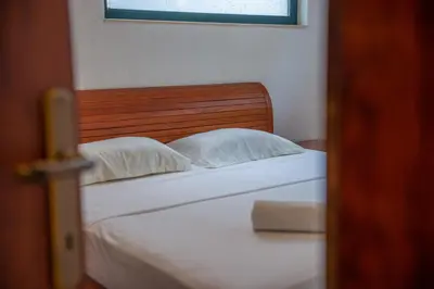 a bedroom with a white bed with a wooden headboard at BigBen Apartments in Ulcinj
