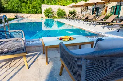 a table and chairs next to a swimming pool at Boutique hotel Ruzmarin SPA & Garden by Aycon in Budva